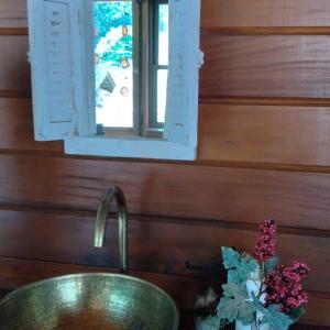 La salle de bains est pourvue d'un lavabo, d'une fenêtre et d'un vase de fleurs. dans l'établissement Pousada Recanto Viva a Vida, à Domingos Martins
