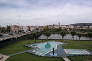 a swimming pool in a park next to a river at Grande Hotel Dom Dinis in Mirandela