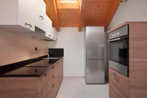 a kitchen with wooden cabinets and a stainless steel refrigerator at Appartamenti al Canton in Colà di Lazise