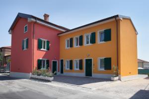 a red orange and yellow building with green doors at Appartamenti al Canton in Colà di Lazise