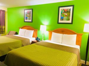 two beds in a room with green walls at Classic Suites - Cleveland in Cleveland