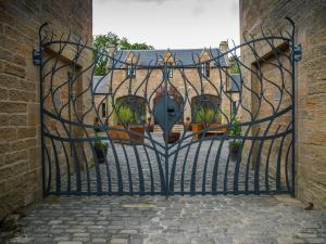 an open gate to a building with potted plants at Coach House Ratho Park Steading in Ratho