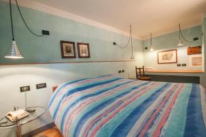 a bedroom with a bed with a colorful striped blanket at Albergo Al Tempo Perduto in Bagolino