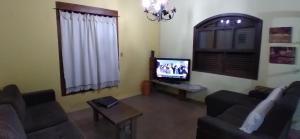 uma sala de estar com um sofá e uma televisão em Ilhabela 150m da praia em Ilhabela