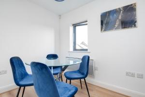 una sala de reuniones con mesa de cristal y sillas azules en 2 Bed Family Apt w/BALCONY & PARKING! ☆ FREE NETFLIX - With 50 Inch Smart TV, FREE NETFLIX & WIFI - Birmingham City Centre, By 02 Academy, Cube & Mailbox, en Birmingham