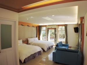 um quarto de hotel com duas camas e uma cadeira azul em Natural Residence B&B em Tai'an
