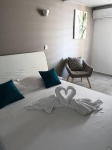 uma cama branca com dois corações em cima em MARS ET VENUS LOCATION - piscine privée et chauffée em Sainte-Marie