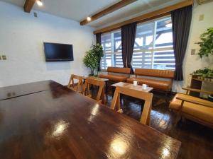 una sala de estar con una gran mesa de madera y un sofá en Keimichi Guest House en Hakuba