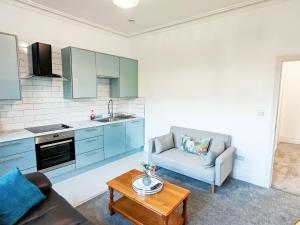 a kitchen with blue cabinets and a couch and a table at C-New Flat,4 Adults,20 mins to Beach,Netflix,Wifi in Bournemouth