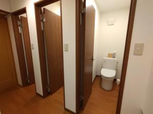 a bathroom with a toilet and a wooden door at Keimichi Guest House in Hakuba +10 photos