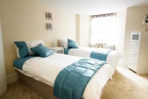 two beds with blue pillows in a bedroom at Heritage City - Central New Town Apartment in Edinburgh