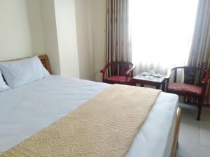 1 dormitorio con 1 cama con 2 sillas y 1 mesa en Khách sạn Sơn en Thái Nguyên