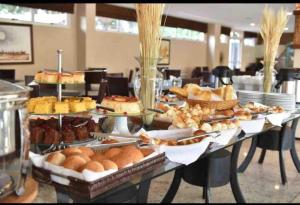 a table filled with different types of bread and pastries at Gran Lençóis Flat Residence in Barreirinhas