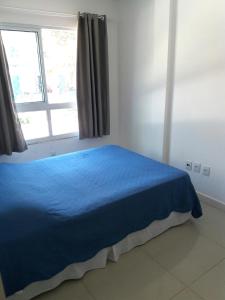 Un dormitorio con una cama azul y una ventana en Canasvieiras - Residencial Costa do Mar, en Florianópolis