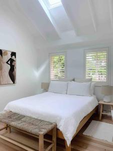 a white bedroom with a large bed and two windows at Casa Parker Stunning 3bdrm apartment in Killcare in Killcare