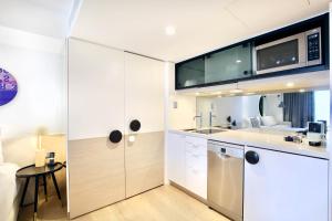 a kitchen with white cabinets and a microwave at Miss Baker's Boutique Accommodation Bondi in Sydney