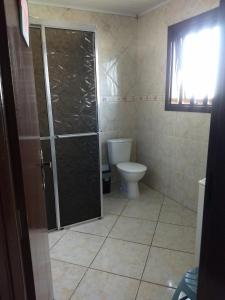 a bathroom with a toilet and a glass shower door at Pousada Atlântica stay home in Tramandaí +50 photos