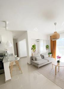 Sala de estar blanca con sofá y mesa en OASIS Punta Cana Apartment, en Punta Cana