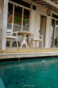 a table and chairs on a porch next to a pool at Java Wood in Gili Trawangan
