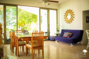 - une salle à manger avec une table, des chaises et un canapé bleu dans l'établissement Casa Pucté Bacalar, à Bacalar