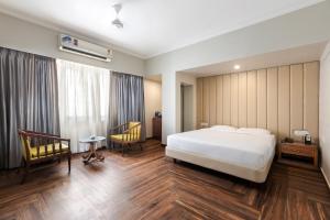une chambre d'hôtel avec un lit, une table et des chaises dans l'établissement GRAND KALINGA HOTEL, à Bangalore