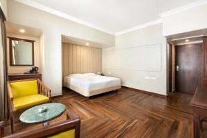 a bedroom with a bed and a table and a chair at GRAND KALINGA HOTEL in Bangalore