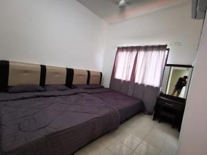 um quarto com uma cama com um cobertor roxo e um espelho em Happy homestay pulau pangkor em Kampong Sungai Udang