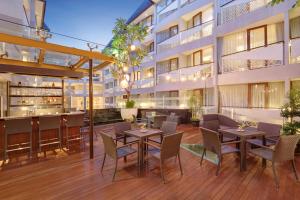 an outdoor patio with tables and chairs in front of a building at Episode Kuta Bali in Kuta
