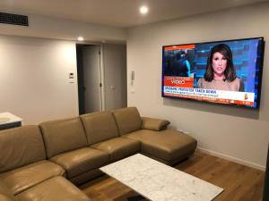 a living room with a couch and a flat screen tv at Waters Edge Apartments in Warners Bay