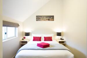 a bedroom with a large white bed with red pillows at Vita Nova Motel in Christchurch
