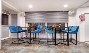 a dining room with blue chairs and tables and a window at Treebo Trend Finesta Suites, Nagpur Airport in Nagpur