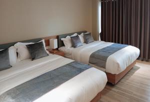 ダバオシティにあるSans Hotel at The Luxebridge Suites Davaoのベッド2台と窓が備わるホテルルームです。