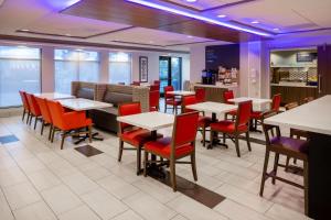 Holiday Inn Express - Coventry S - West Warwick Area, an IHG Hotel في كوفنتري: غرفة طعام مع طاولات وكراسي حمراء