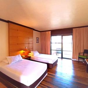 a hotel room with two beds and a window at Sutra Beach Resort, Terengganu in Batu Rakit