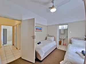 a bedroom with two beds and a bathroom at Fairway Holiday Accommodation in Hermanus