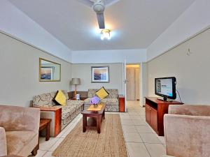 a living room with a couch and a tv at Fairway Holiday Accommodation in Hermanus