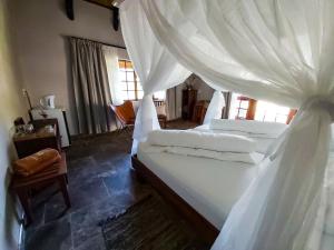 a bedroom with a large bed with white curtains at Sophienhof Lodge in Outjo