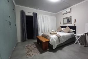 a bedroom with a bed and a table and a window at De Dane Guestroom in Bloemfontein