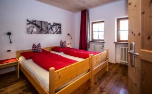 a bedroom with a large wooden bed with red sheets at Editlodge "Dessot" in Badia