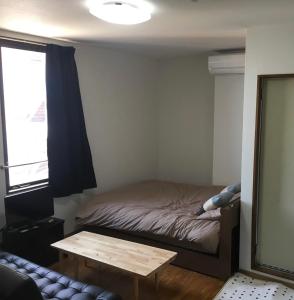 niewielka sypialnia z łóżkiem i stołem w obiekcie コンドミニアムホテル Stay inn Blue 301号室 w mieście Hukue