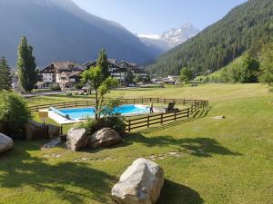 a swimming pool in a field with mountains in the background at Appartamento condominio Ametista - La Thuile in La Thuile