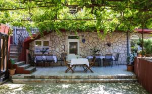 a patio with tables and chairs under a stone building at Guest House J&J in Zaton