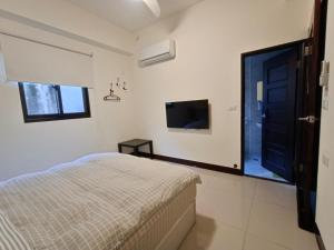 a bedroom with a bed and a flat screen tv at Meet BnB in Luodong