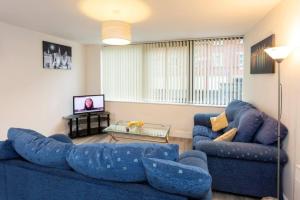 a living room with two blue couches and a tv at Spacious 2 Bed Apartment Norwich, Close To Station and City centre in Norwich