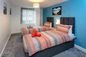 two beds in a bedroom with blue walls at Spacious 2 Bed Apartment Norwich, Close To Station and City centre in Norwich
