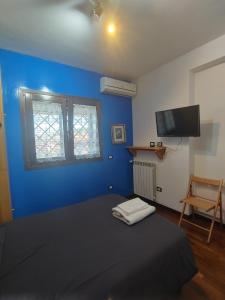 a blue room with a bed and a tv at Nonna Genoveffa, camere in Infernetto