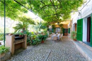 een patio met een tafel, stoelen en planten bij Casa Margarita bis, casa con pisicina en Fornalutx in Fornalutx