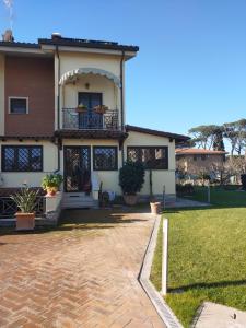 a house with a balcony and a brick driveway at Nonna Genoveffa, camere in Infernetto