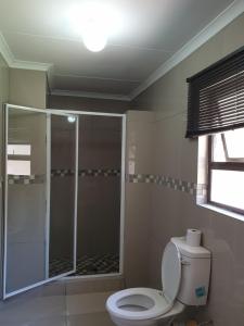 a bathroom with a toilet and a glass shower at Rose Guesthouse Klerksdorp in Klerksdorp