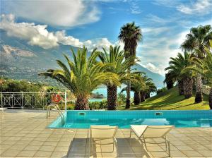 a swimming pool with chairs and palm trees at Sea Wave Villa Kefaloniaprivatevillas in Trapezaki